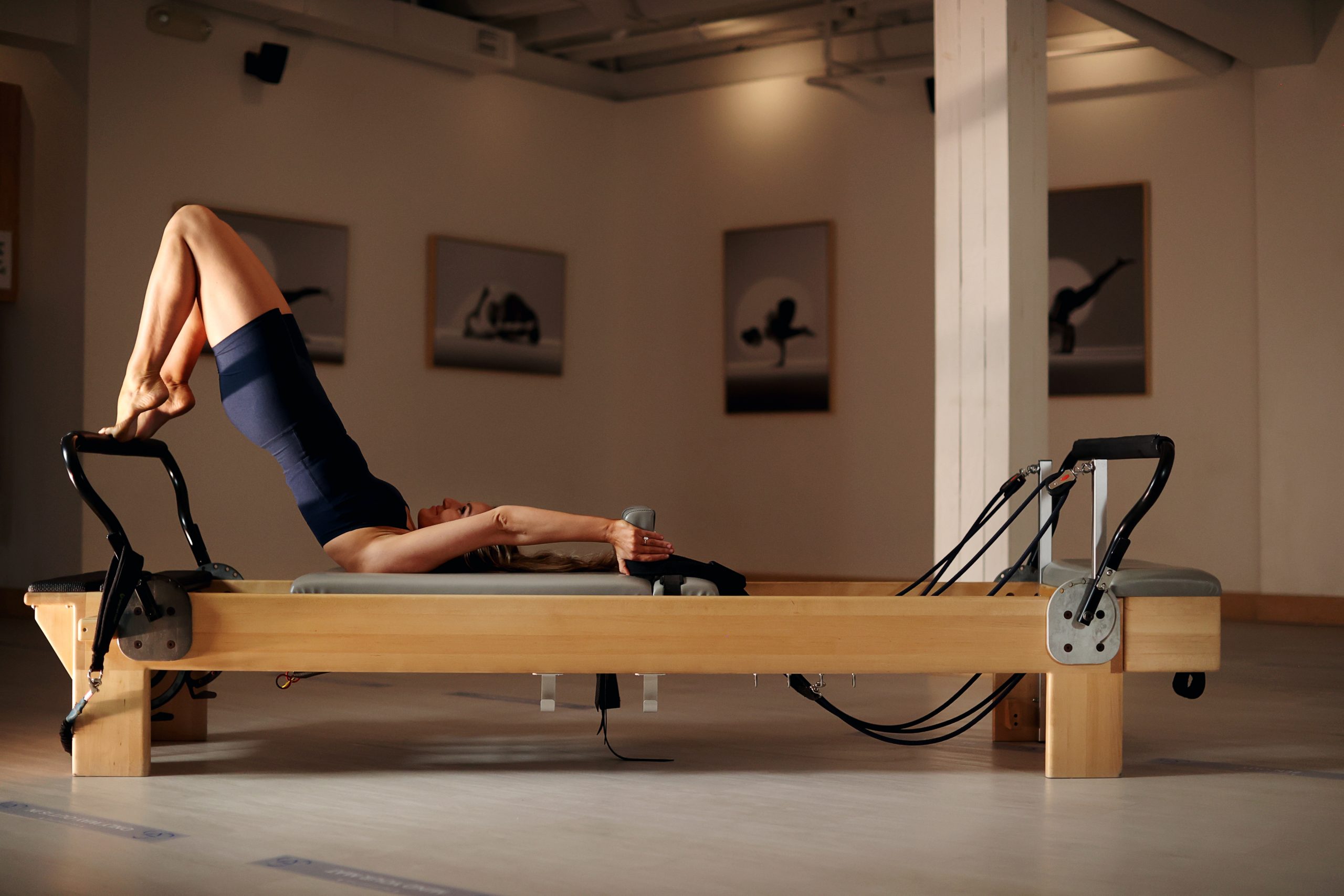 Woman performing Pilates exercise on reformer machine at Ekam Yoga & Pilates in Newport Beach