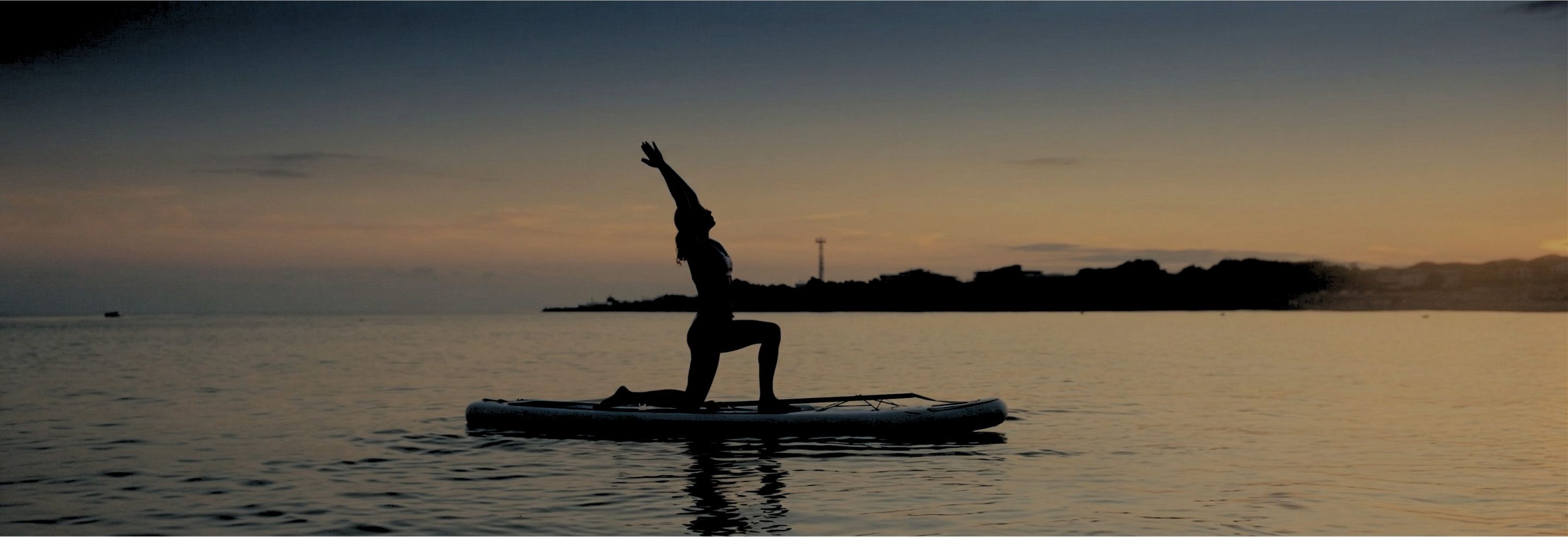 Paddleboard yoga silhouette at sunset over Newport Bay